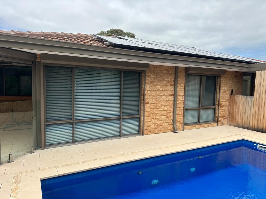 Large grey roller shutters on poolside windows - manual vs electric choice depends on shutter size.