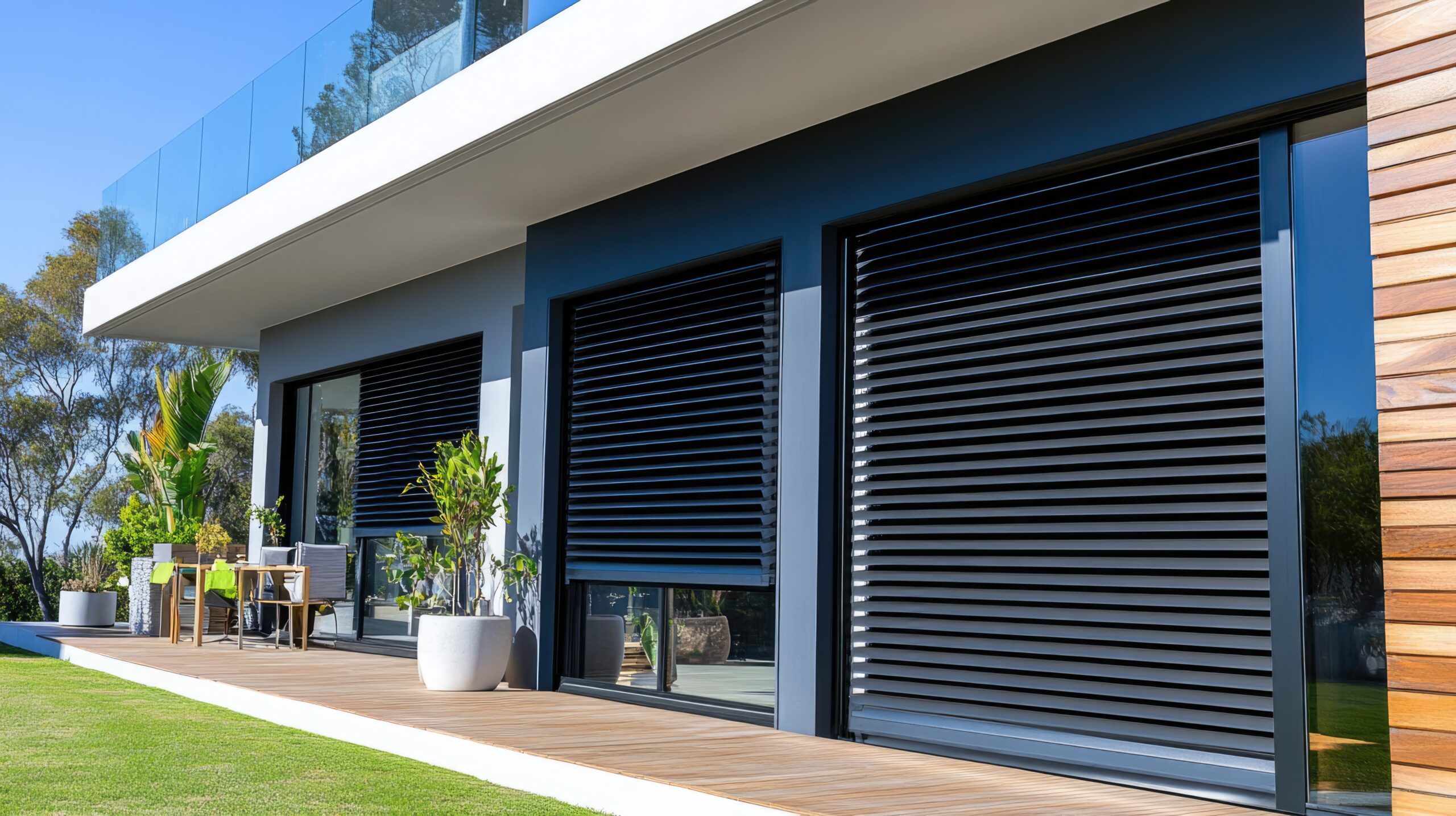 Modern home exterior featuring black roller shutters installed on large sliding glass doors