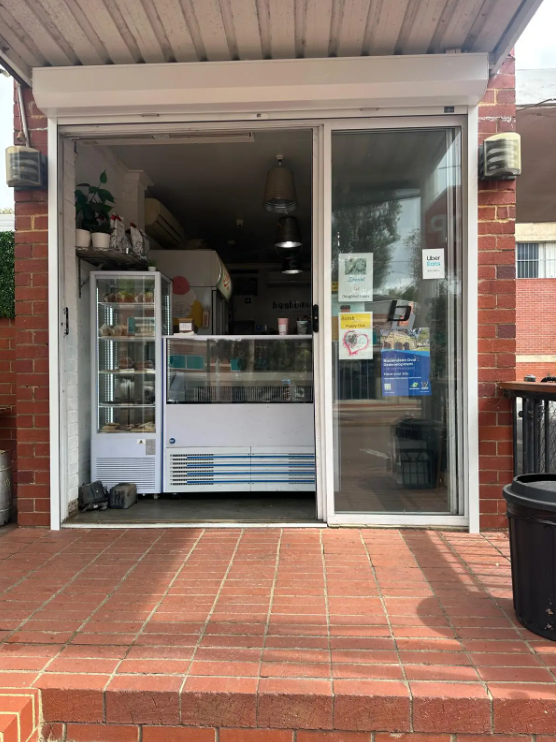 Modern white window roller shutter with horizontal aluminium slats providing solar heat protection and privacy for the business